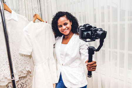 African american woman blogger standing in front of camera recording herself shopping and choosing clothes in a store.fashion shopping and social media conceptの写真素材