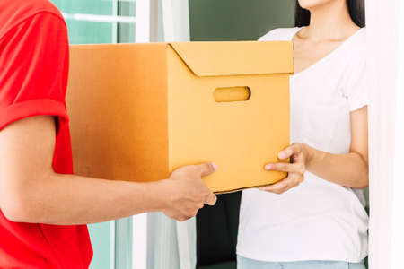 Woman accepting a delivery boxes from delivery man in red uniform.courier service conceptの写真素材