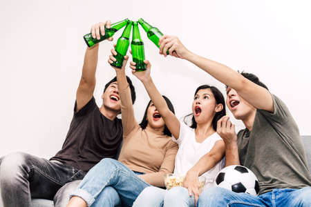 Group of friends eating popcorn and drinking beer together on sofa at home.Friendship and party...