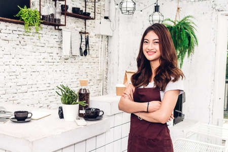 Portrait of woman barista small business owner smiling behind the counter bar in a cafeの写真素材
