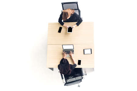 Top view of business people sitting use technology together of laptop and tablet computer checking social apps and working on wooden desk at office.Communication conceptの写真素材