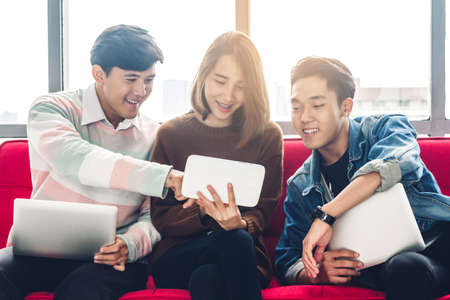 Group of business sitting relax use technology together of smartphone and laptop computer checking social apps and working on brick wall background.Communication conceptの写真素材