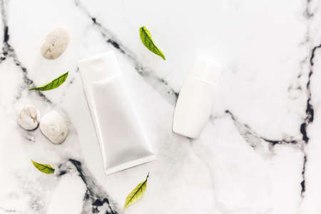 Cosmetic bottle skin care products with spa stones and leaves on white marble background.flat layの写真素材
