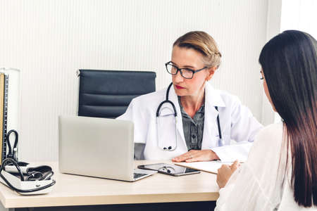 Doctor discussing and consulting with female patien on doctors table in hospital.healthcare and medicineの写真素材
