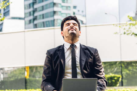 Handsome businessman in black elegant suit sitting and working with laptop computer on the city.Business and startup idea conceptの写真素材