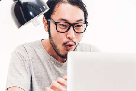 Happy man relaxing and using digital laptop computer on the bed at home.man checking social apps and working.wireless technology conceptの写真素材
