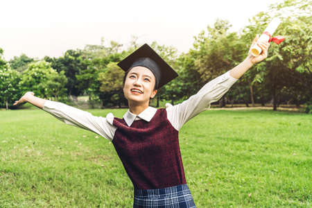 Successful of student young woman and bachelor gowns with diplomas graduate at park in the university.Celebrating graduation and education conceptの写真素材