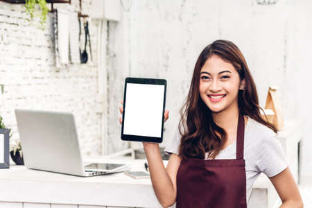 Portrait of woman small business owner smiling and standing with tablet computer in the cafe or coffee shop.woman barista standing at cafeの写真素材