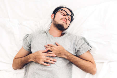 Tired man sleeping after work on a comfortable bed in his bedroom at homeの写真素材