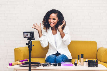 African american woman blogger in front of camera recording vlog herself talking about with makeup cosmetics for internet social networks at homeの写真素材