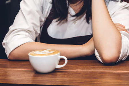 Woman holding coffee latte art on wooden table in coffee shop