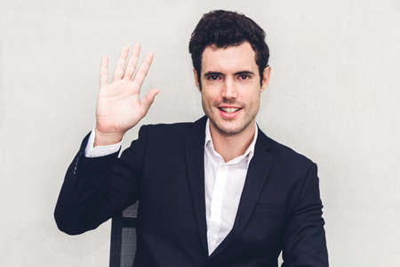Man smiling at camera waving and saying hello to youの写真素材