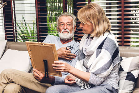 Senior couple relaxing and talking together sitting on sofa in living room at home.Retirement couple conceptの写真素材