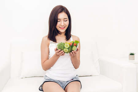 Happy woman eating and showing healthy fresh salad in a bowl.dieting concept.healthy lifestyle with green foodの写真素材