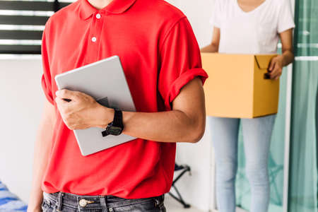Woman accepting a delivery boxes from delivery man in red uniform.courier service concept