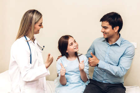 Doctor looking at camera while young family father and little girl  on background togetherの写真素材