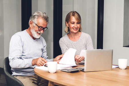 Senior couple reading documents and calculating bills to pay in living room at home.Retirement...