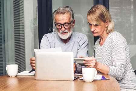 Senior couple reading documents and calculating bills to pay in living room at home.Retirement...