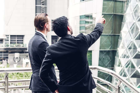 Two smiling businessman coworkers in black suit talking and walking.business people discussing strategy in the modern cityの写真素材
