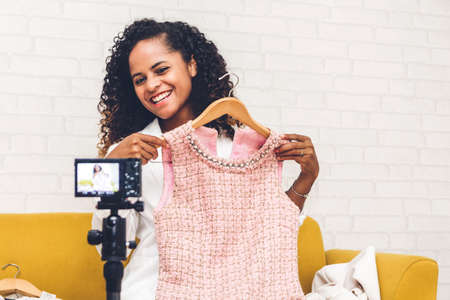 African american woman blogger in front of camera recording vlog herself talking about with clothes at home.fashion shopping and social media conceptの写真素材