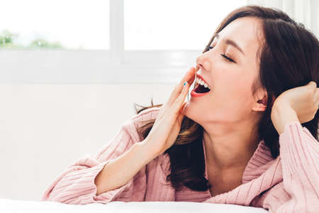 Portrait of happy smile asia woman enjoy and relax on the bed in bedroom at home.asian beautyの写真素材