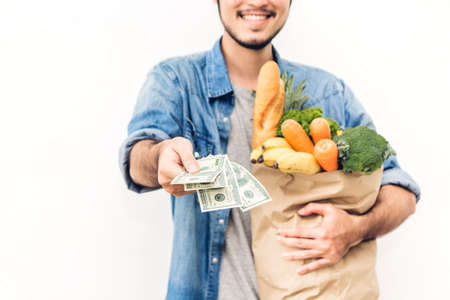 Man holding shopping paper bag with fruit and vegetables on white backgroundの写真素材