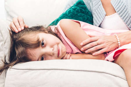 Mother with little daughter having fun and playing with mom on the sofa at home.Love of family and...