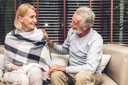 Senior couple relaxing and talking together sitting on sofa in living room at home.Retirement couple conceptの写真素材