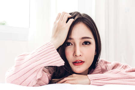 Portrait of happy smile asia woman enjoy and relax on the bed in bedroom at home.asian beautyの写真素材