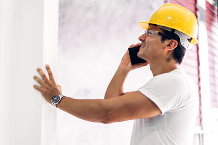Young construction engineer in a yellow helmet working and  looking job for planning project at building home siteの写真素材