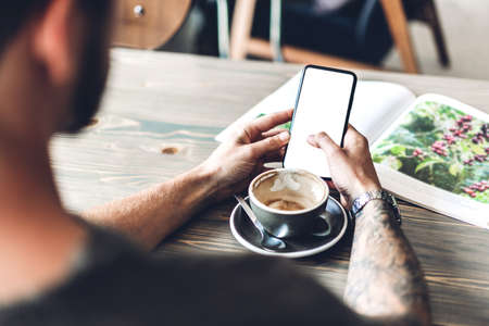 Man use smartphone and reading book with coffee at table in cafe.Communication and technology conceptの写真素材