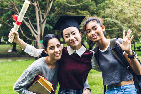 Successful of student young woman and bachelor gowns with diplomas graduate hugging her friend at university.Celebrating graduation and education conceptの写真素材
