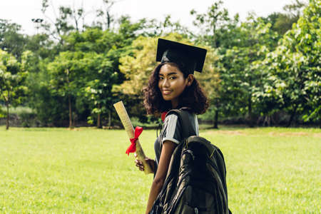 Successful of student young woman and bachelor gowns with diplomas graduate at park in the university.Celebrating graduation and education conceptの写真素材
