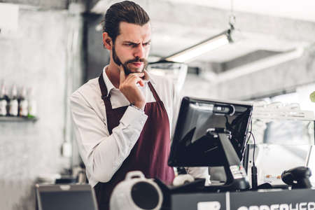 Portrait of handsome bearded barista man small business owner working behind the counter bar in a cafeの写真素材