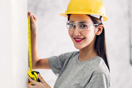 Young woman construction engineer in a yellow helmet working and  looking job for planning project at building home siteの写真素材