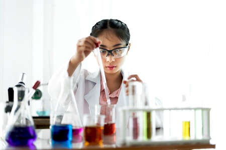 Teenage girl students learning and doing a chemical experiment and holding test tube in hands in science class on the table.Education conceptの写真素材