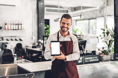 Portrait of barista man small business owner standing with tablet computer with mockup blank in the...