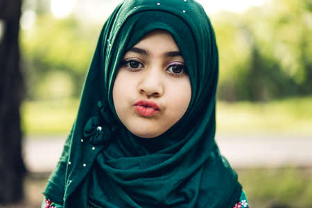 Portrait of happy little muslim girls child with hijab dress smiling and looking at camera in the...