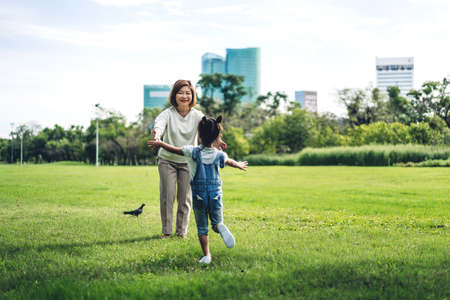 Portrait of happy grandmother and little cute girl enjoy relax together in summer park,little girl run to grandmother and hug.Family and togethernessの写真素材
