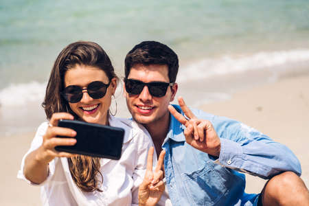 Romantic lovers young couple relaxing together on the tropical beach.Man and woman taking selfie...