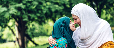 Portrait of happy muslim mother and little muslim girls child  with hijab dress smiling and enjoy relax in summer park.Education conceptの写真素材