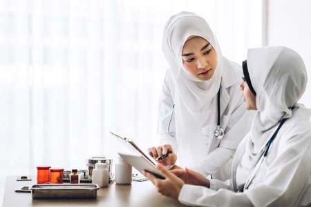 Muslim two asian woman freelancer sme business online shopping working on laptop computer with cardboard box on table at home - Business online shipping and delivery conceptの写真素材