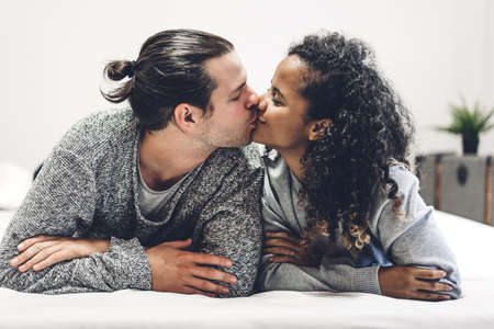 Young happy couple smile and have fun lying in bed together at homeの写真素材