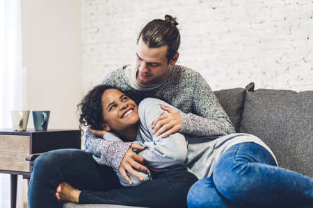 Young happy couple smile and have fun lying in bed together at home
