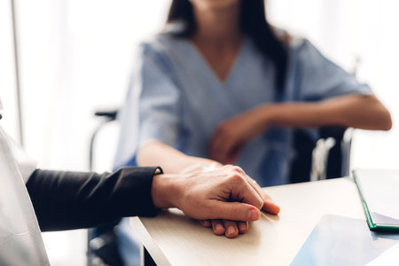 Woman doctor consulting and holding hand patient reassuring with care on doctors table in...