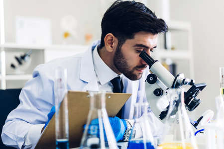 Professional scientist man doing a chemical experiment while making a research and using microscope...