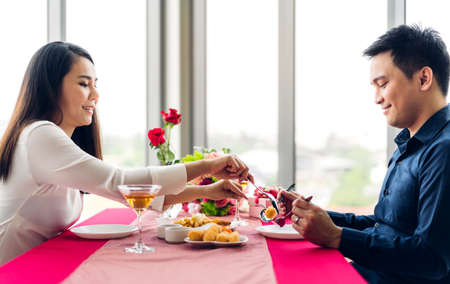 Beautiful couple in love and enjoying together eating meal sitting in the Restaurantの写真素材