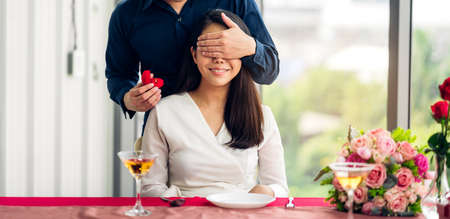 Young handsome man giving ring for surprise to girlfriend and talking together in the restaurantの写真素材