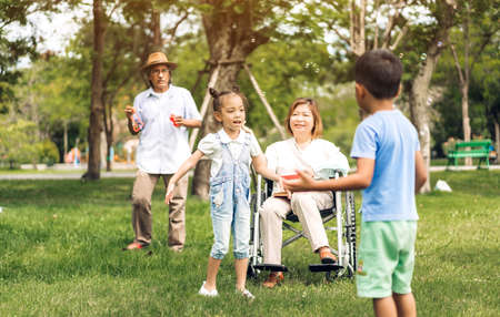 Portrait of happy grandfather with grandmother and little cute girl enjoy relax in summer park.Young girl with their laughing grandparents smiling together.Family and togethernessの写真素材