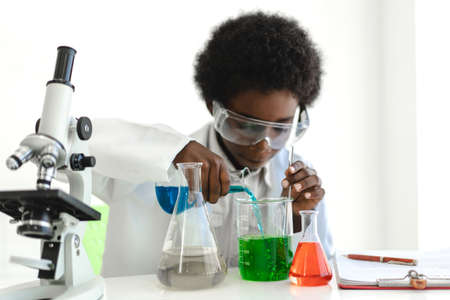 African american boy students learning and doing a chemical experiment and holding test tube in hands in science class on the table.Education conceptの写真素材